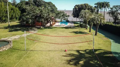Gramado com quadra de vôlei e a piscina ao fundo